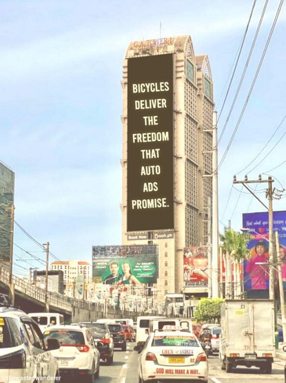 Bild einer mit Autos verstopften Straße in Manila. Am Hochhaus im Hintergrund hängt ein gigantisches Plakat mit der Aufschrift "BICYCLES DELIVER THE FREEDOM THAT AUTO ADS PROMISE.", also Grob übersetzt: Fahrräder bieten die Freiheit, die Autowerbung verspricht.

Es sieht aber stark nach Photoshop aus.