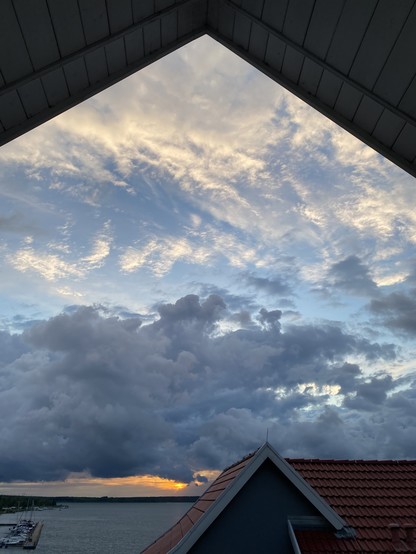 Ausblick aus einer Dachgaube zum Sonnenuntergang mit Wolken