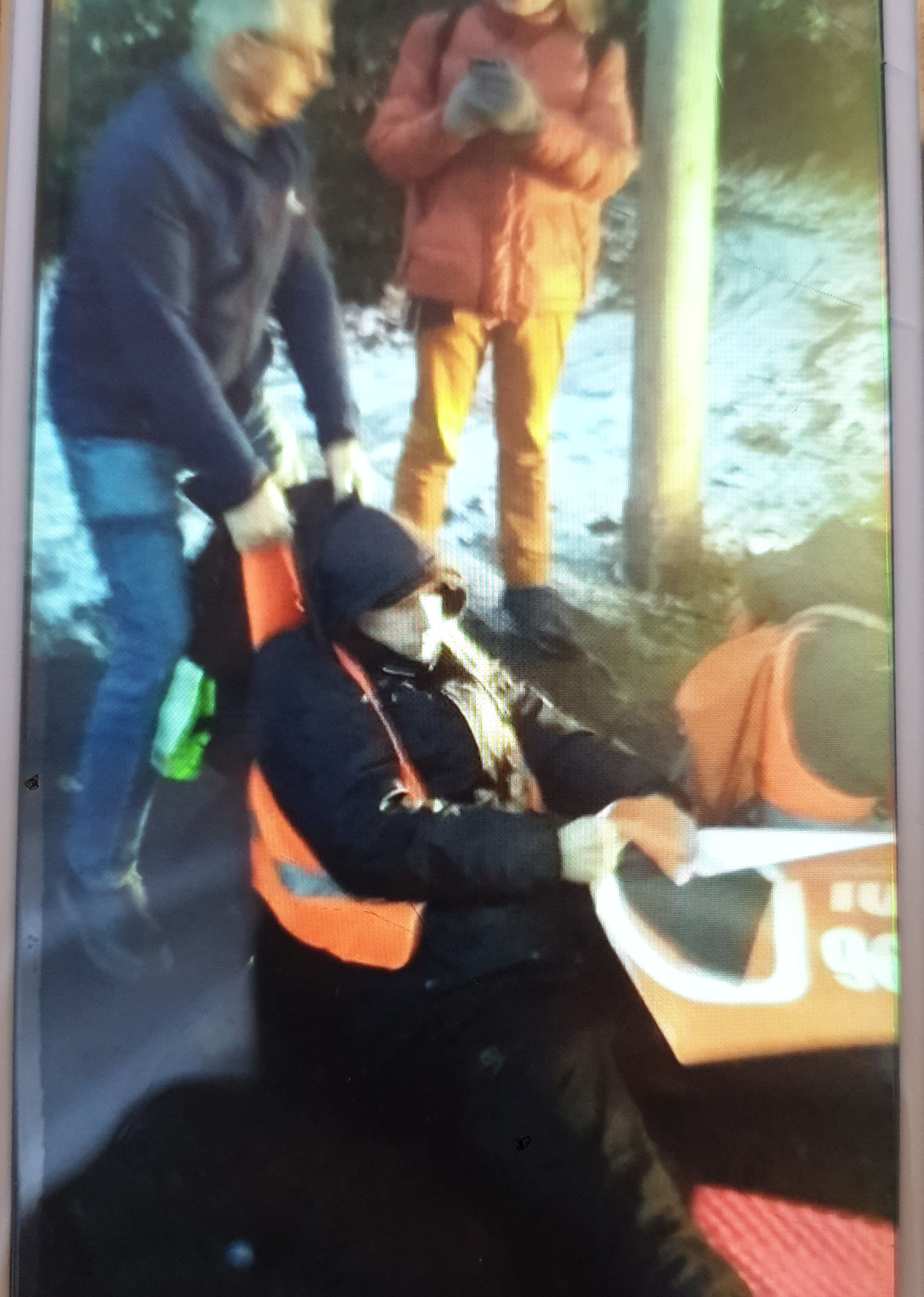 Ein Mann schleift einen anderen, der sich noch an einem Transparent festhält, von der Straße.
Im Hintergrund filmt ein Mensch.
Es liegt Schnee.