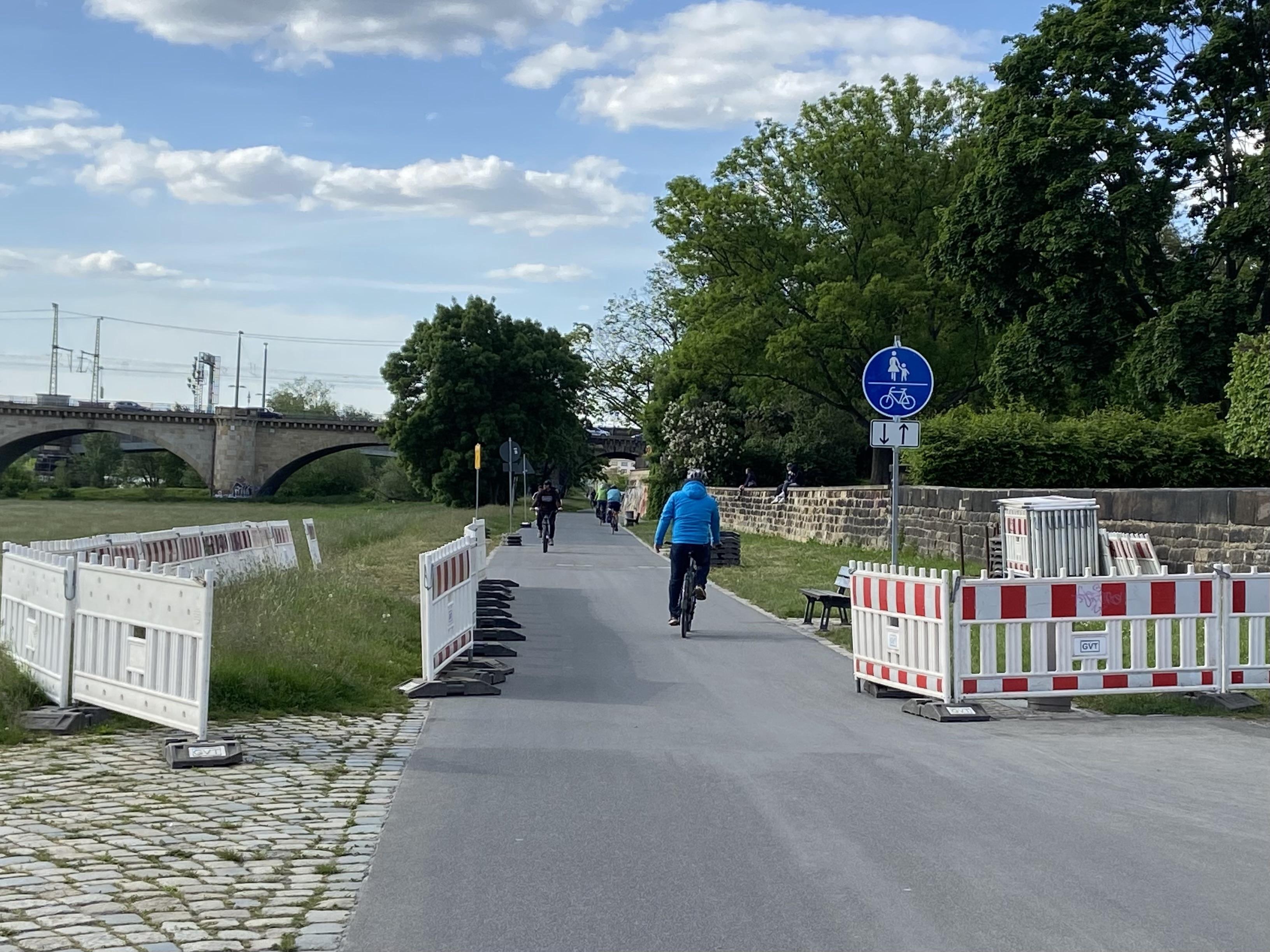 Schilder und Baustellenzäune entlang der Straße des Elberadwegs. Viele Fahrräder sind unterwegs. Schilder und Baustellenzäune entlang der Straße des Elberadwegs. Viele Fahrräder sind unterwegs.