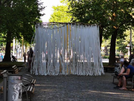 Ein Bild zeigt eine Art Fransenvorhang auf die gesamte Breite des mittleren Weges der Hauptstraße in Dresden, dort kommt keinE RadfahrerIn vorbei.