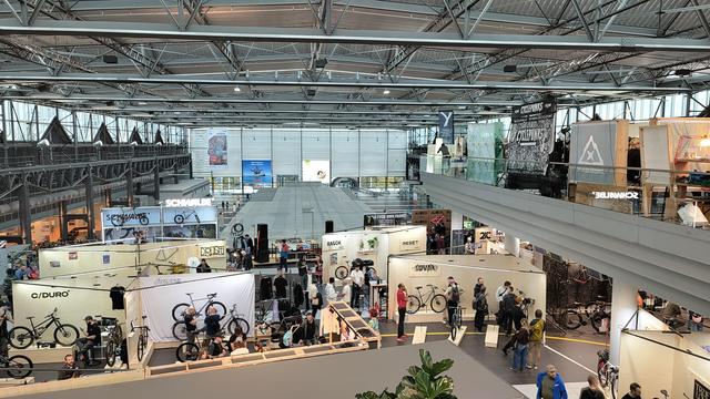 Ein Blick in die Flughafenhalle. Man sieht viele Messestände mit Fahrrädern und Menschen dazwischen. 