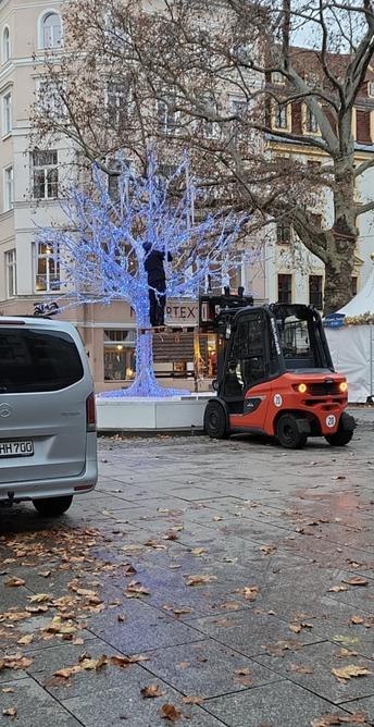 Ein blauer LED-Baum wird auf einem Weihnachtsmarkt installiert. 