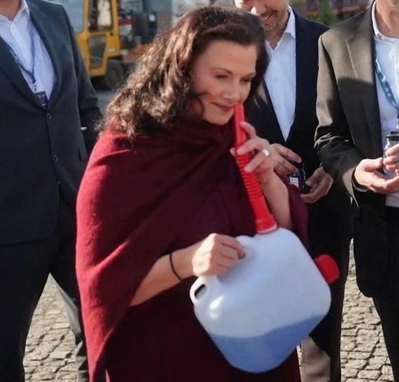 CDU-Politikerin Gitta Connemann hält den Ausgießer eines Kraftstoffkanisters an ihre Nase und riecht daran. In der zugrunde liegenden Videoszene schnuppert sie mehrfach am Inhalt und äußert sich anerkennend über dessen Geruch. Mehrere Personen in Anzügen stehen lächelnd im Hintergrund.