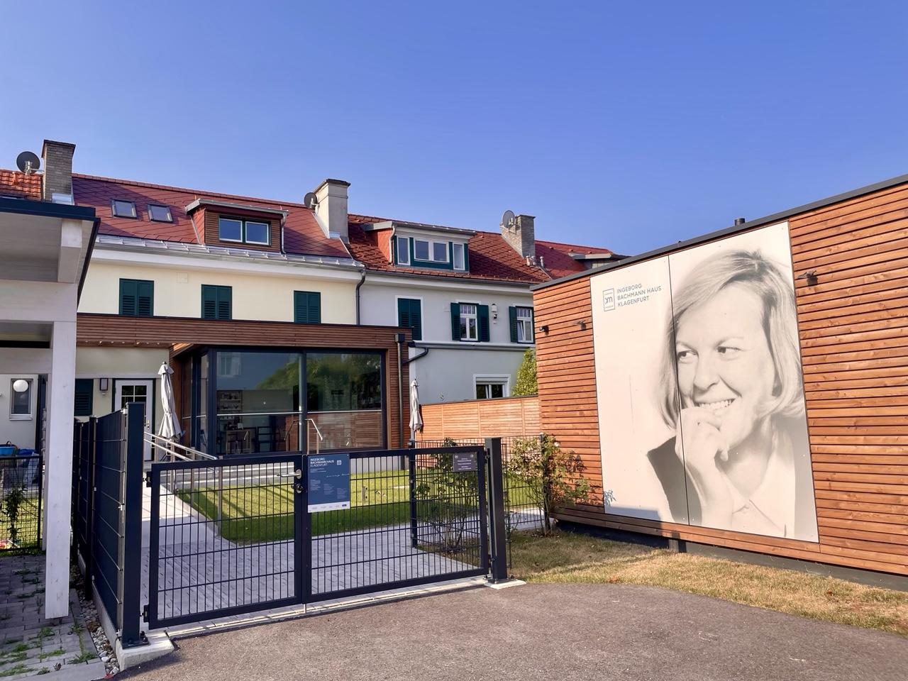 Die Hinteransicht vom Laubenweg aus: rechts ein großes Plakat mit einer Abbildungen Ingeborg Bachmanns