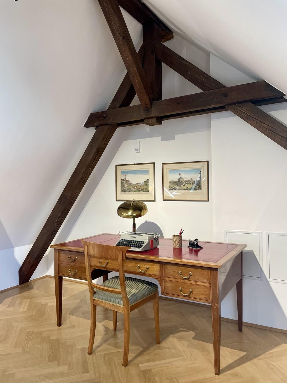 Original Ingeborg Bachmann Inventar in der Henselstr. 26:
Schreibtisch, Stuhl, Schreibmaschine, Stifteköcher und Locher sowie eine Schreibtischlampe im Zimmer unterm Dach