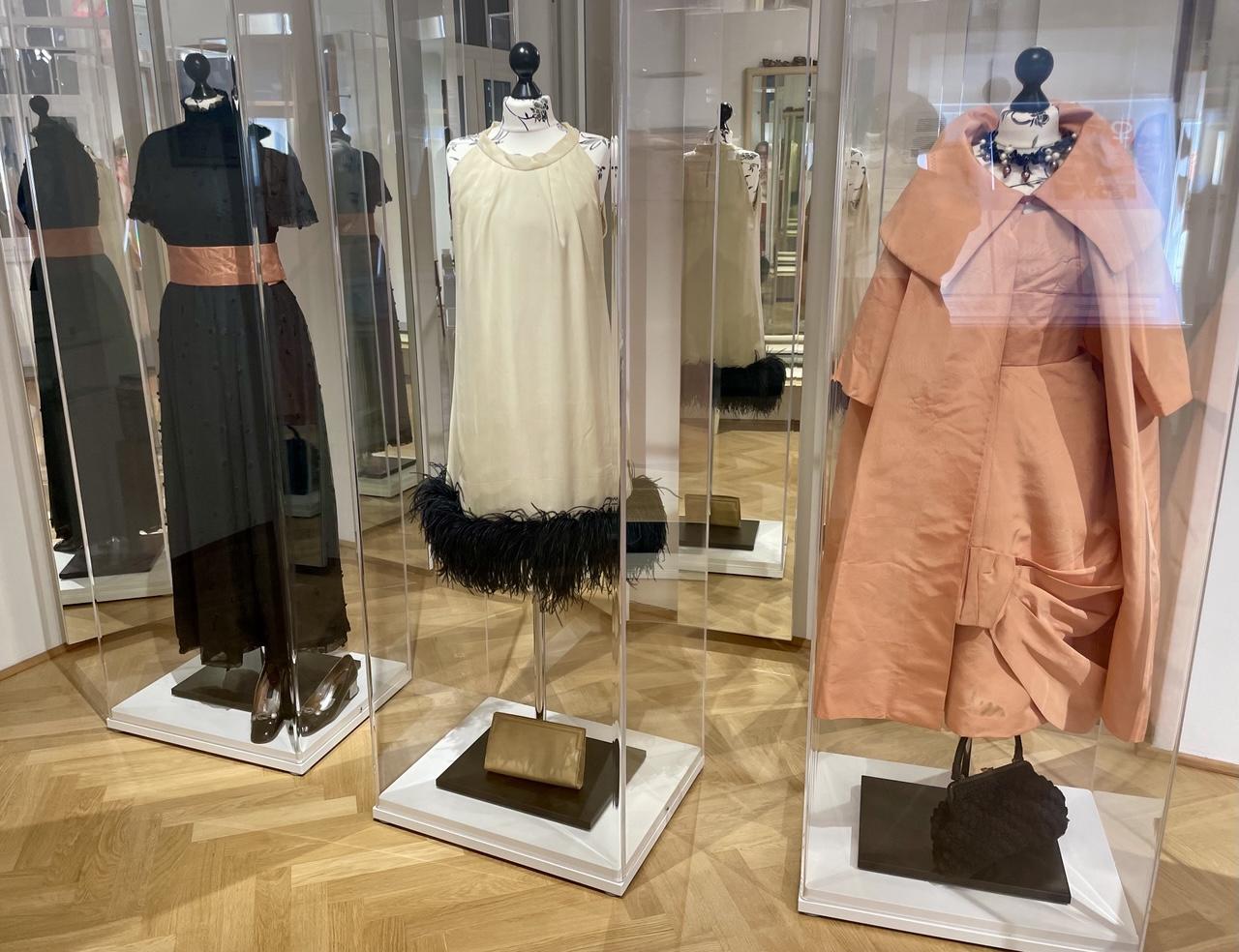Kleider, die Ingeborg Bachmann trug:
Links ein langes schwarzes Kleid mit passenden Schuhen, in der Mitte ein creme-weißes Kleid mit schwarzem Rand dazu eine Handtasche, rechts ein lachsfarbenes Kleid und eine schwarze Handtasche