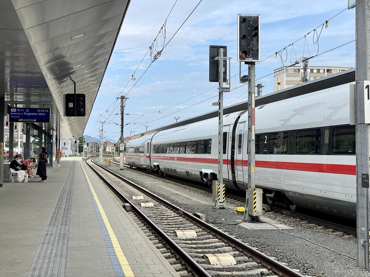 Bahnsteig 4 mit leerem Gleis und Anzeige RJ659 9:02 9:11 Flughafen Wien
Auf Gleis 3 steht ein ICE mit Ziel Münster.
Der Himmel reißt so langsam auf und wird blau.