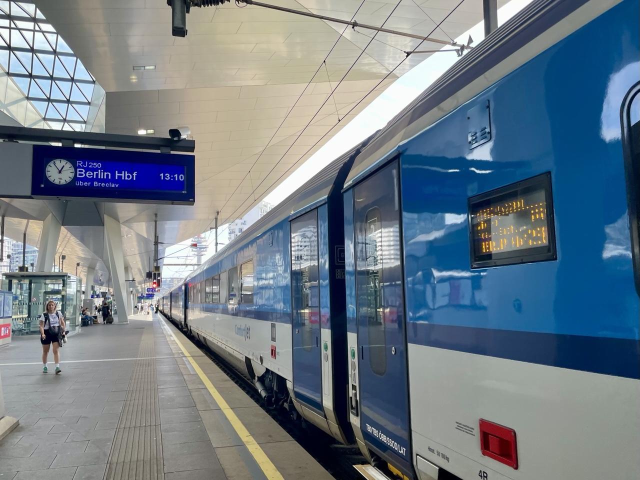 Blau weißer Zug der České dráhy am Bahnsteig 12.
Die blaue Anzeigetafel zeigt 6 Minuten vor Eins, RJ250 nach Berlin Hbf über Breclav 13:10