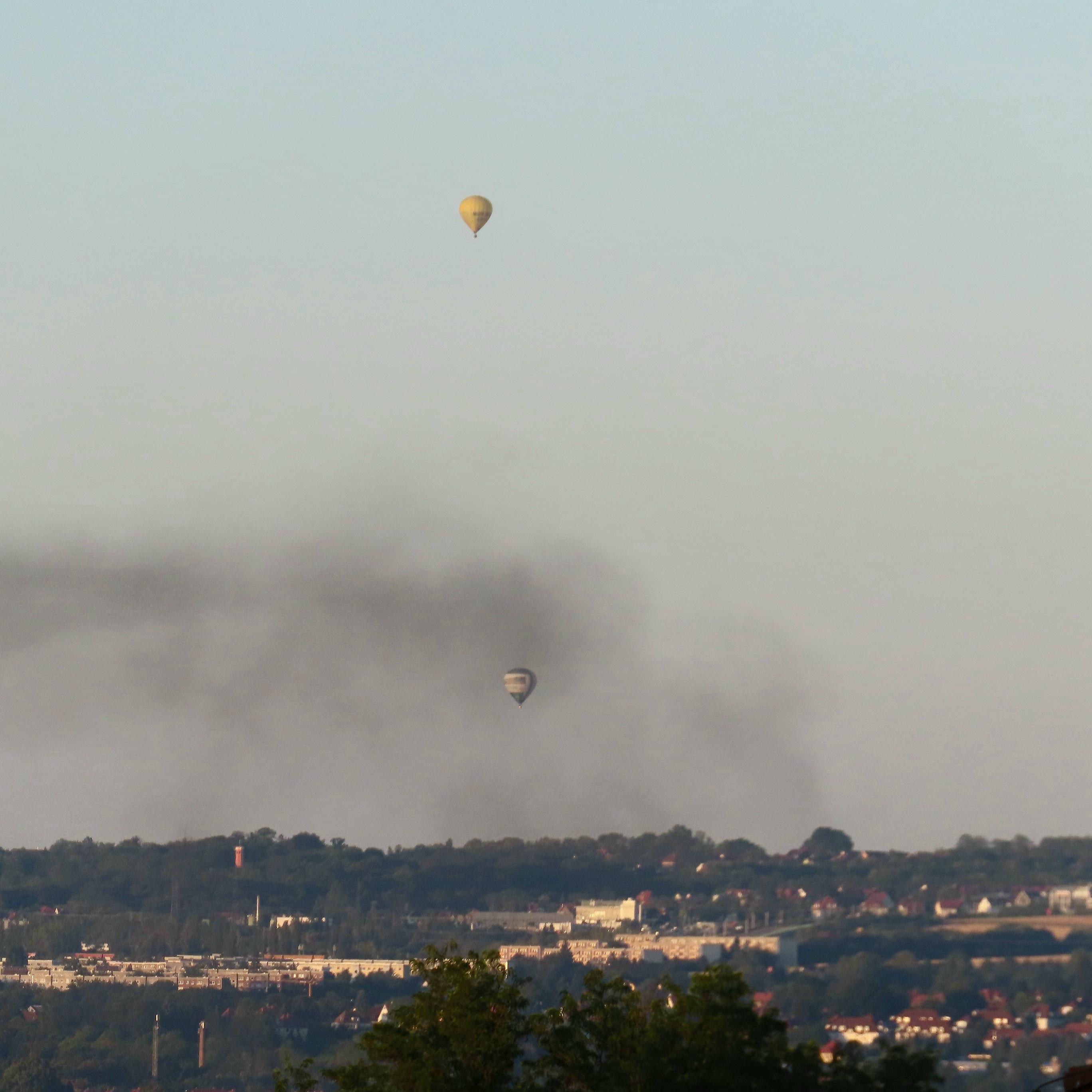Zwei Heißluftballons.

Einer in einer Schleierwolke, die dunkel ist. Ob von Rauch - keine Ahnung